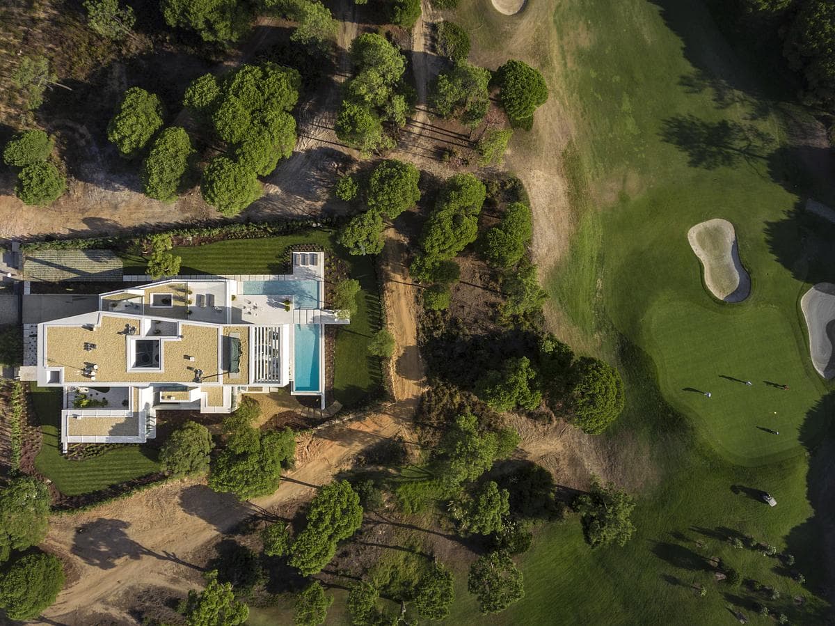 Opulent mansion surrounded by lush gardens, overlooking a pristine golf course retreat.
