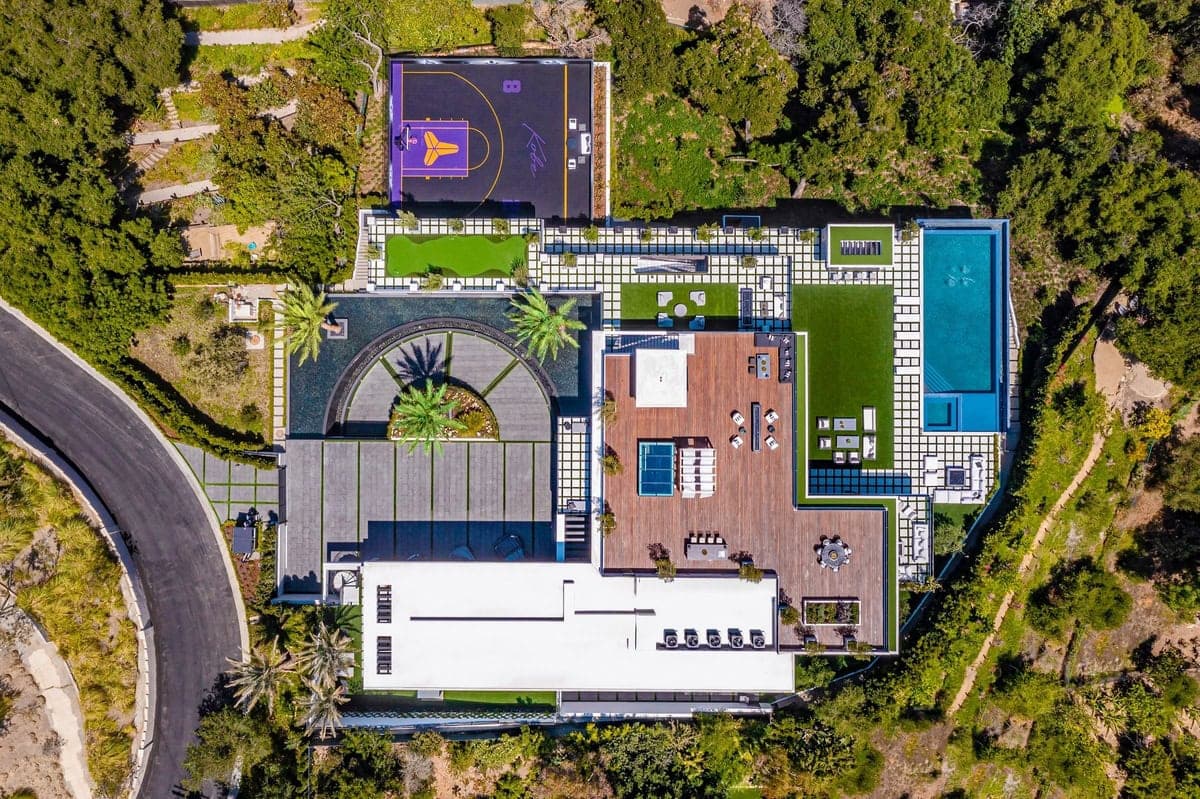 Luxurious modern home with pool and vibrant basketball court in stunning landscaped surroundings.