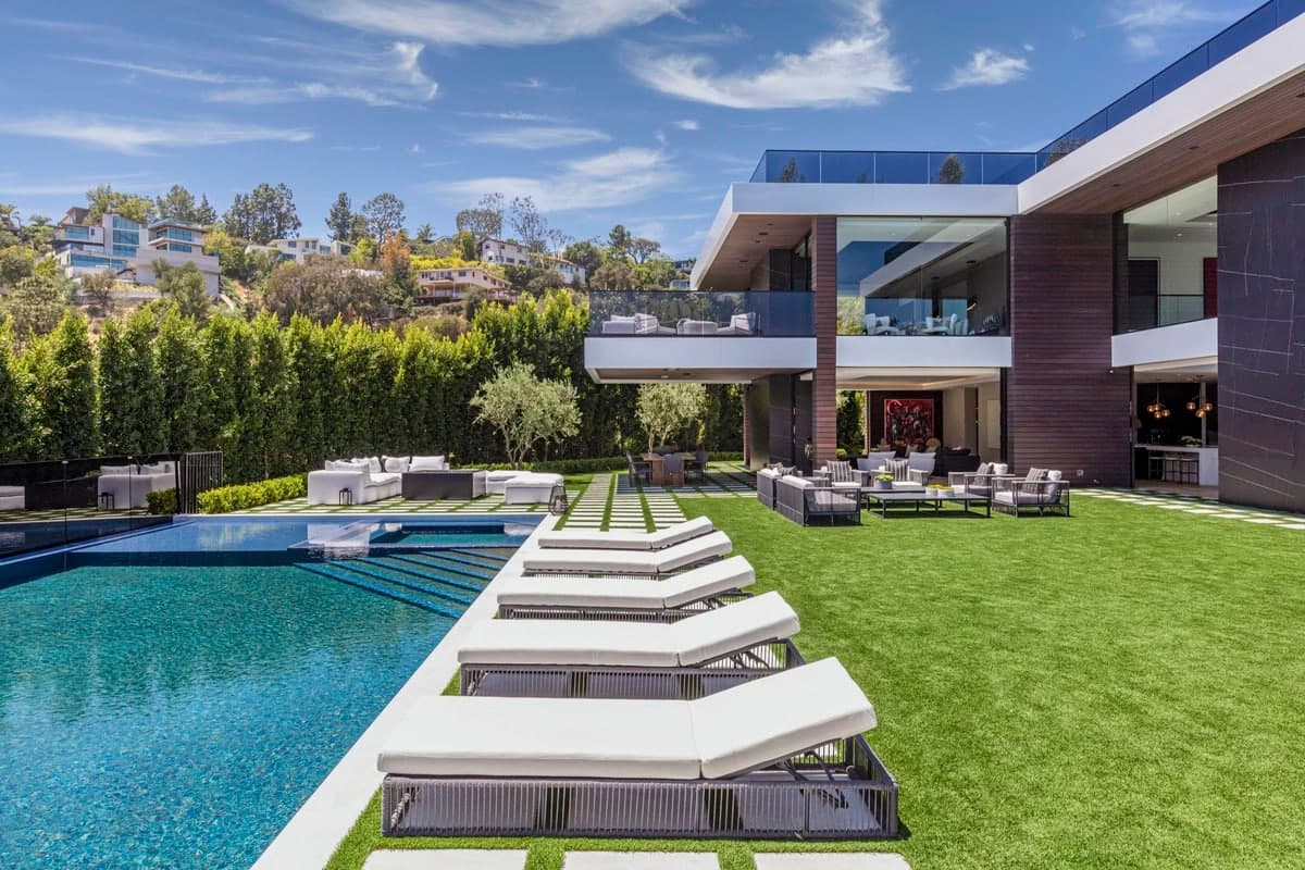 Luxury modern mansion with swimming pool and elegant outdoor living space in serene surroundings.