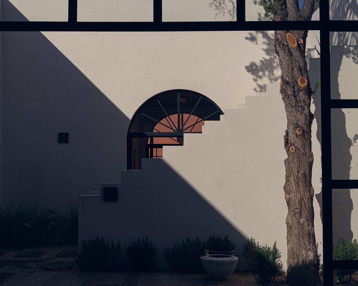 Minimalist architecture blending natural elements, inviting exploration through a serene archway.