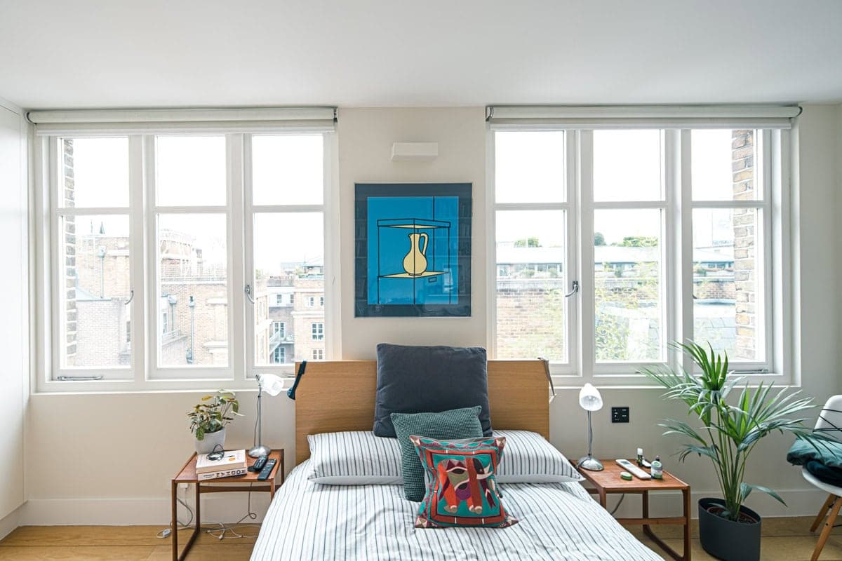 Minimalist bedroom with vibrant artwork, natural light, and stylish decor for a serene atmosphere.