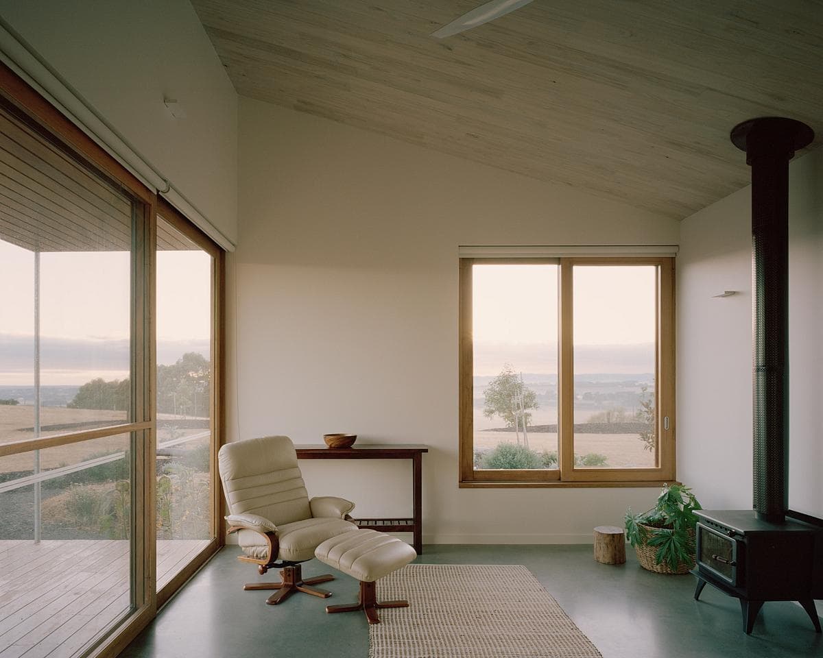 Tranquil minimalist interior with natural light, cozy furniture, and serene outdoor views.