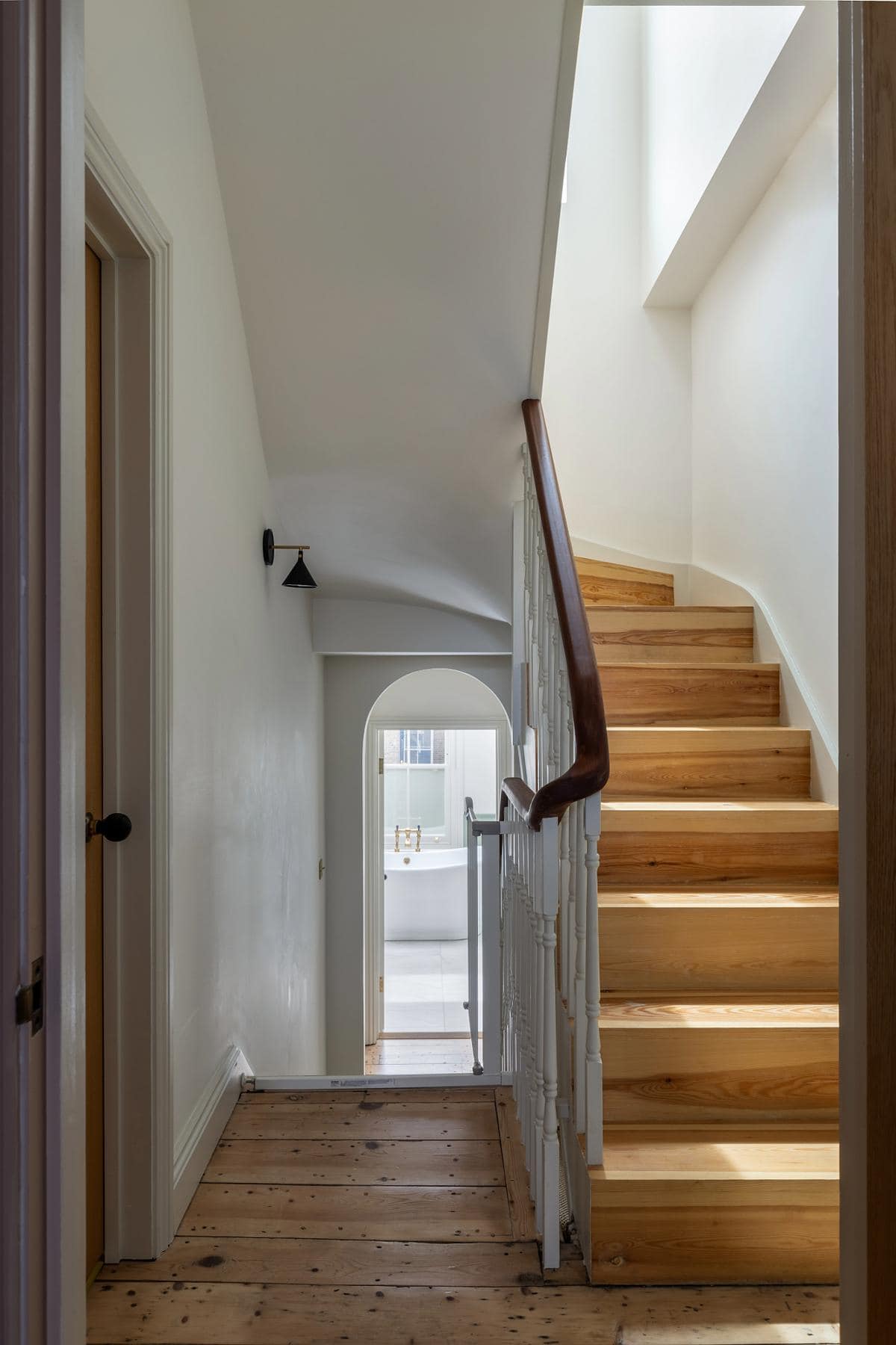 Elegant minimalist staircase bathed in natural light with warm wooden elements.