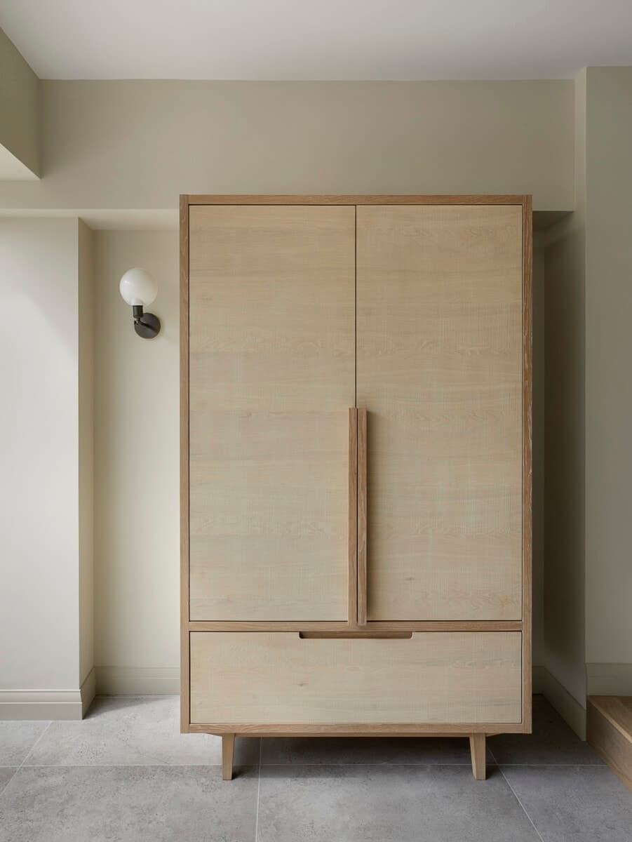 Minimalist wooden wardrobe in light beige room with modern design and sleek lines.