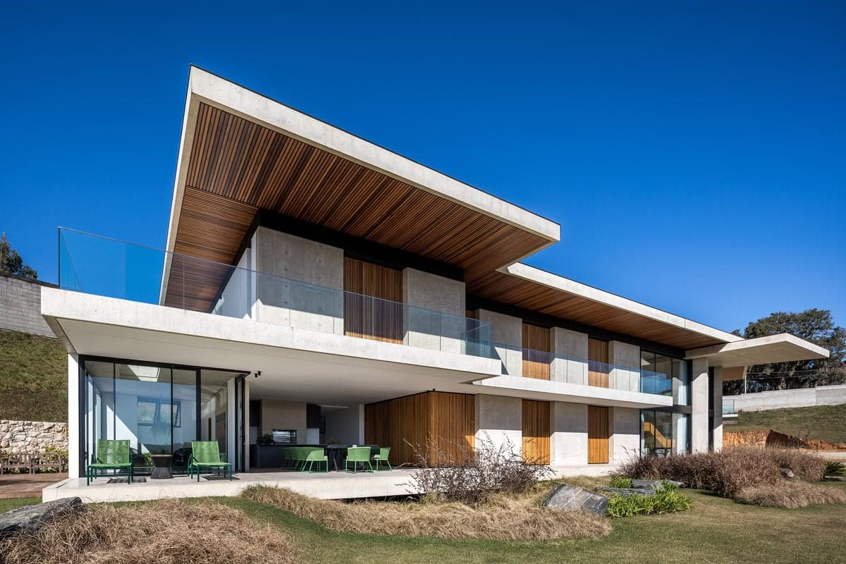 Modern two-story house with expansive glass, wooden accents, and a spacious outdoor patio.
