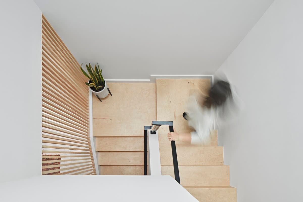 Overhead view of a modern, light-wood staircase with vertical slats and black railing.