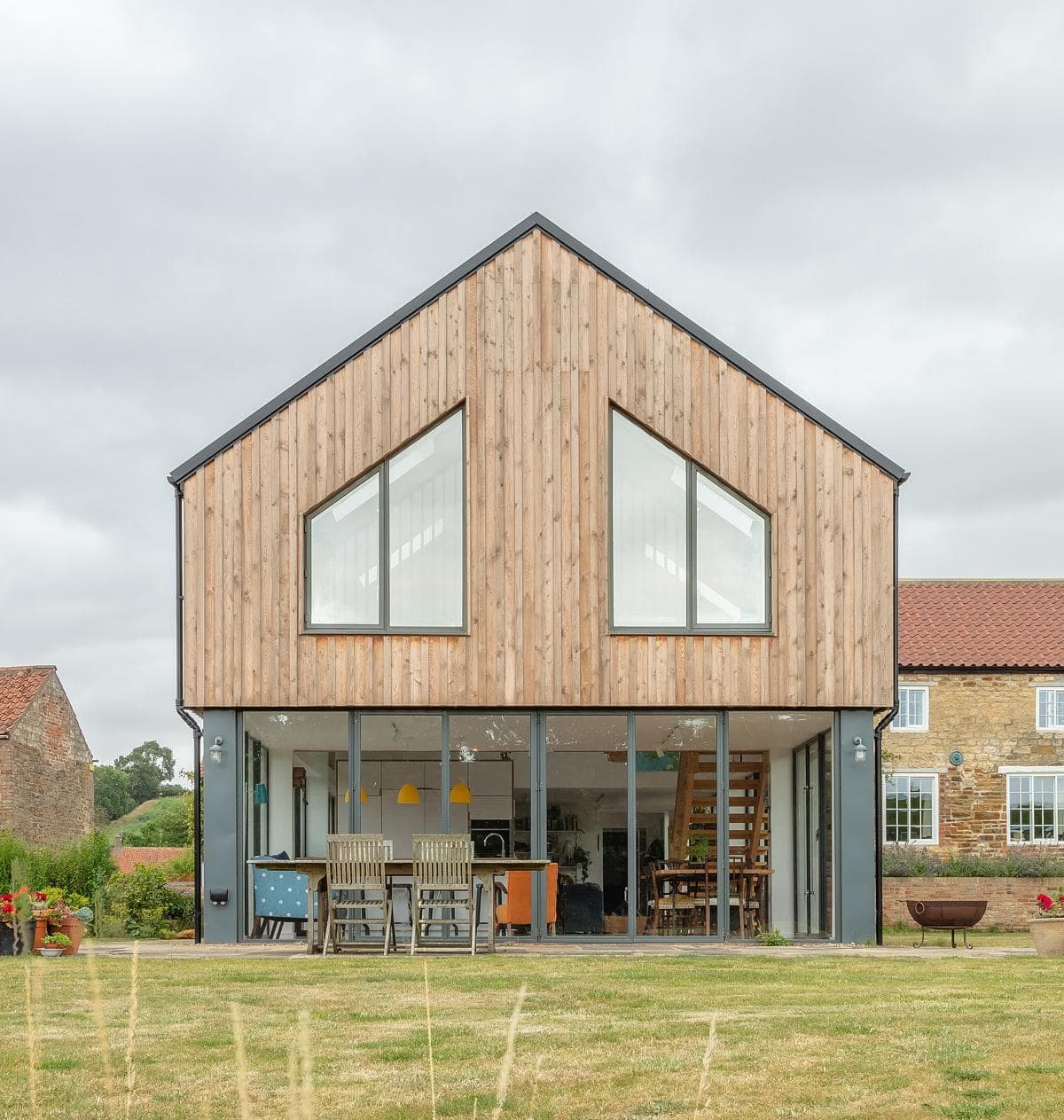 Gabled timber-clad house with large upper-floor windows and a glazed ground floor.