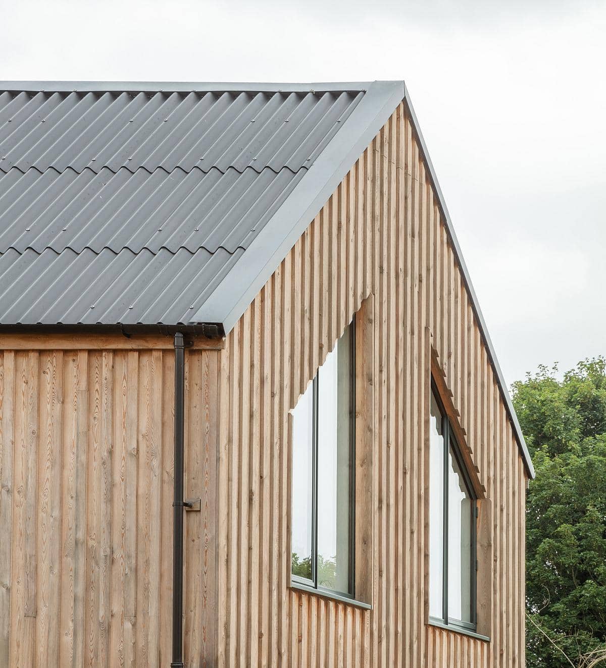Modern gable roof home harmoniously integrating wood and metal within a natural landscape.