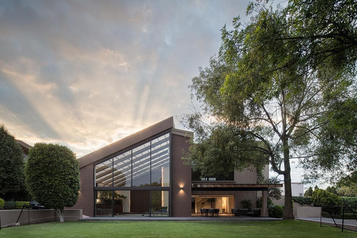 Modern house design with glass and brick facade framed by serene sunset landscaping.