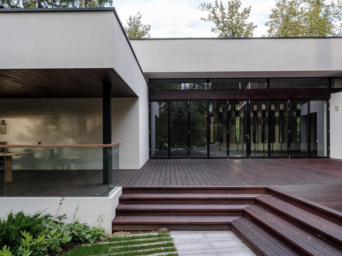 Modern architectural home with elegant design, large glass panels, and inviting wooden deck.