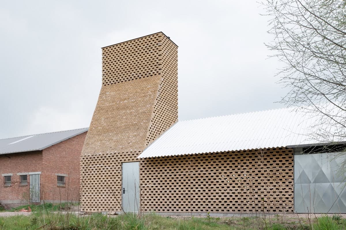 Brick-clad building with a steep roof and tall angular chimney.