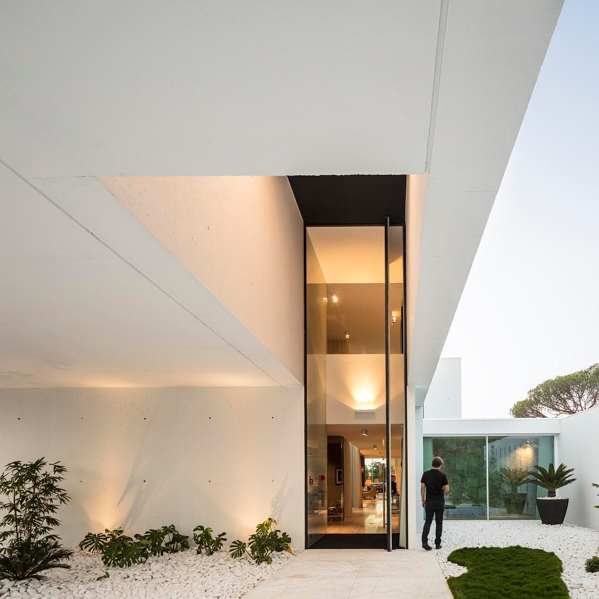 Sleek modern architecture with glass entrance and landscaped surroundings.