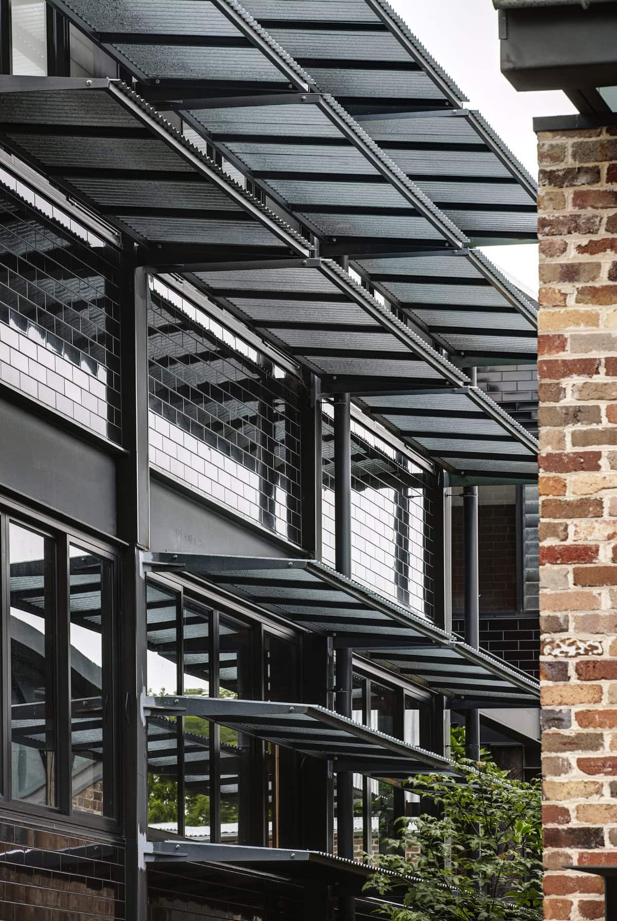 Glazed building facade with dark framing and planting.