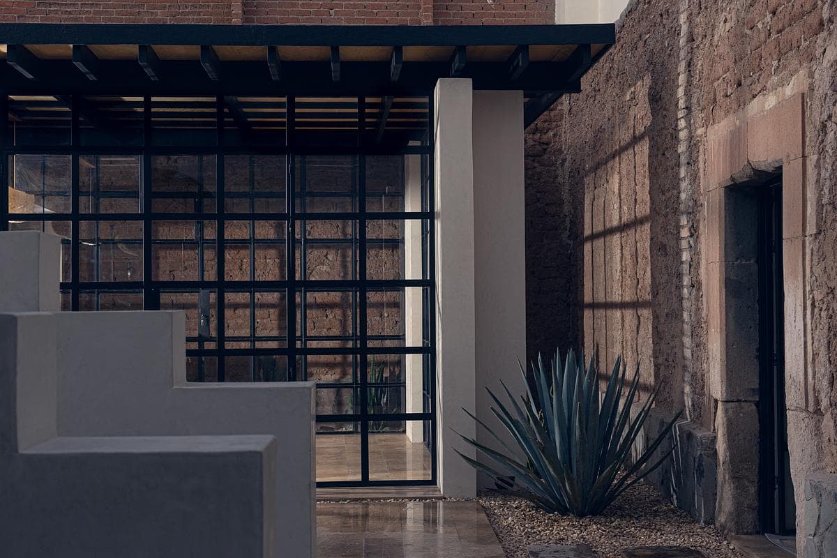 Modern architectural design fuses contemporary glass and historic stone, creating a serene outdoor space.