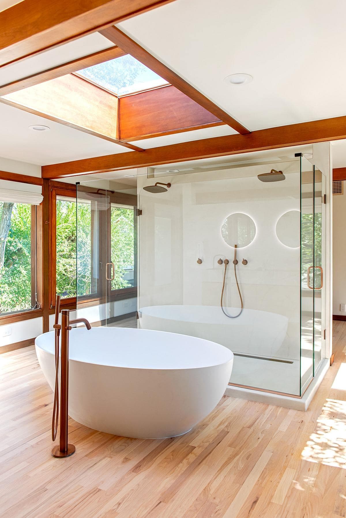Sleek modern bathroom featuring a freestanding tub, skylights, and warm wooden accents.