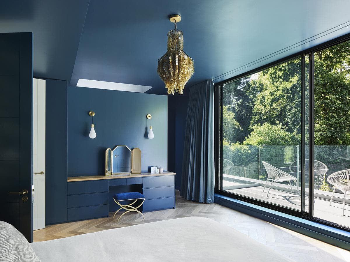 Contemporary blue bedroom with elegant decor and natural light, featuring stylish vanity and serene views.