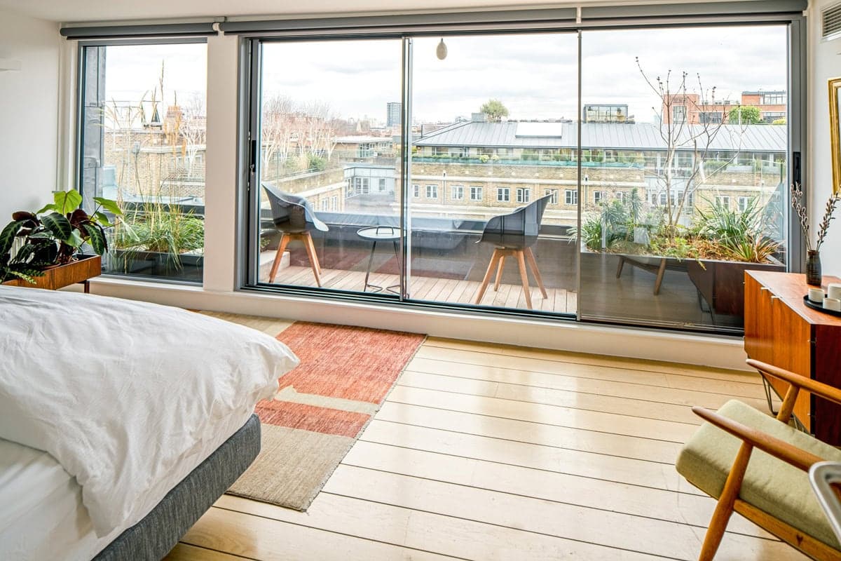 Stylish modern bedroom with balcony, abundant natural light, and serene decor for relaxation.