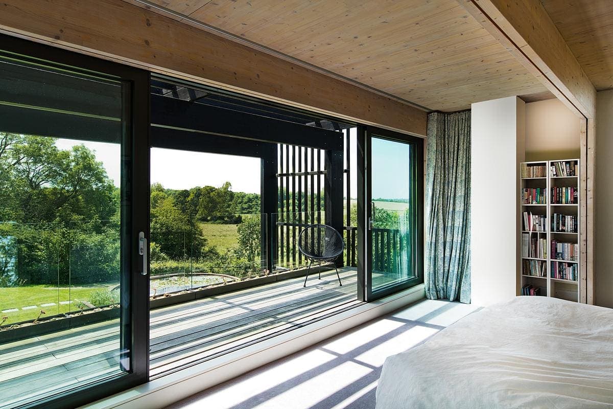 Serene modern bedroom with large windows, inviting nature views and a minimalist design.