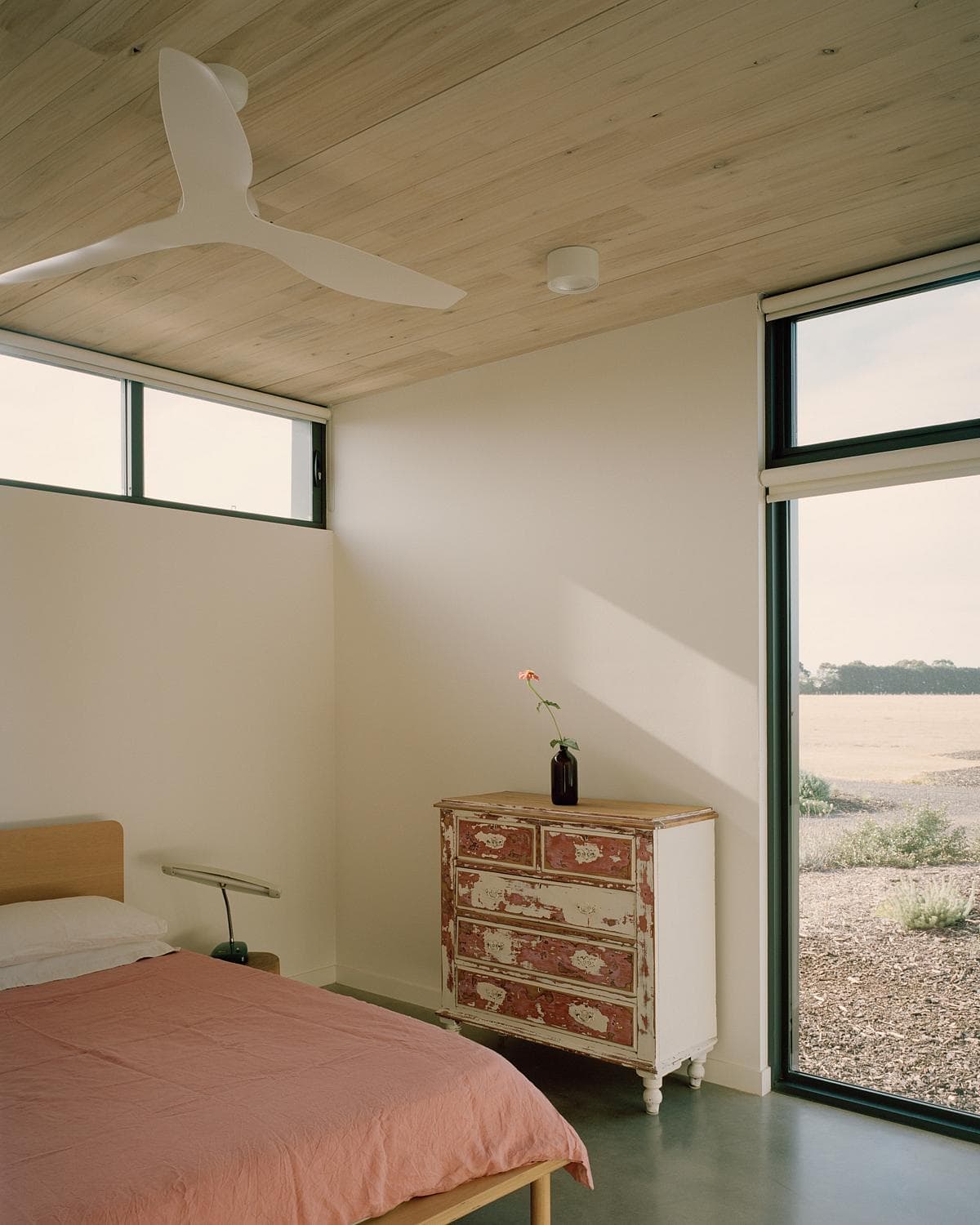 Tranquil modern bedroom with natural light, wooden accents, and vintage character.