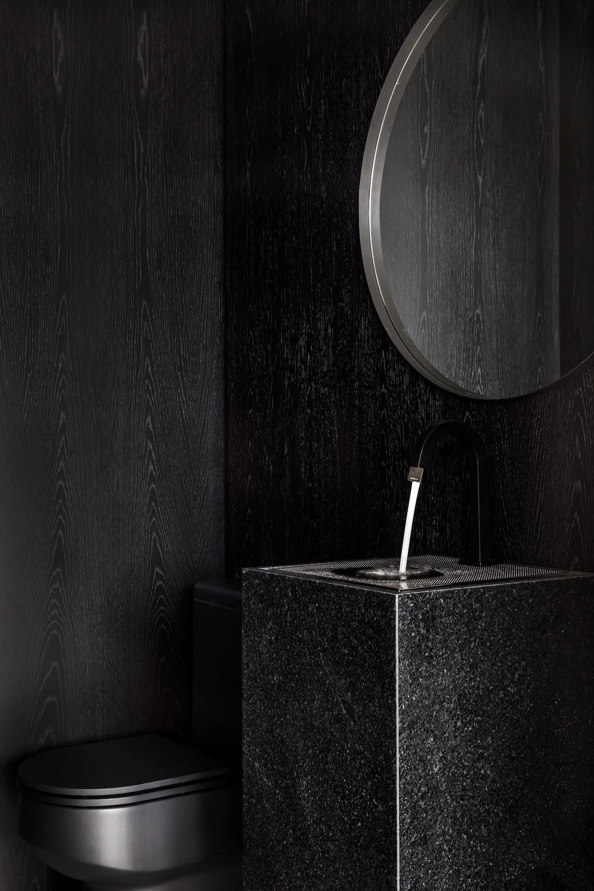 Sophisticated modern black bathroom featuring sleek fixtures and warm textured wood accents.