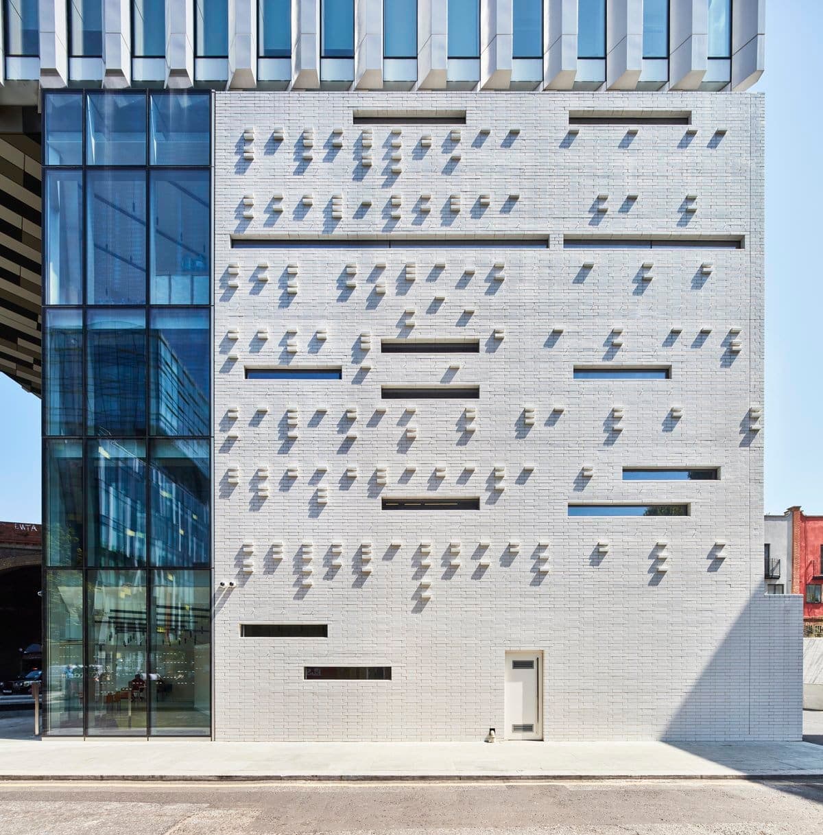 Modern building facade with white brick, protruding elements, and large glass section.