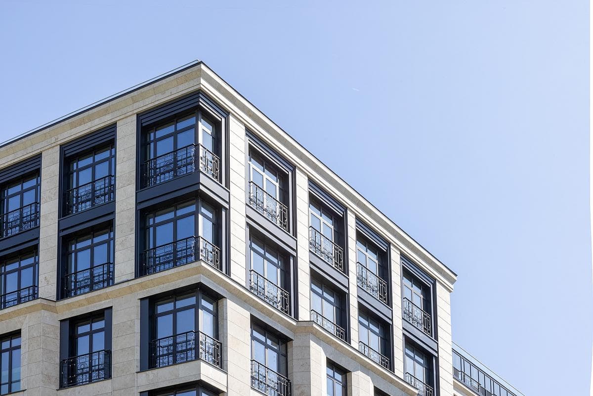Modern, multi-story building with sleek design, light stone, dark-framed windows, and minimalist railings.