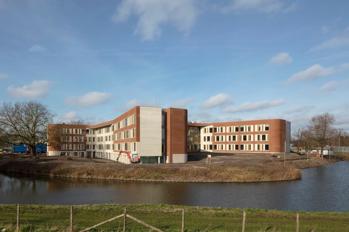 Modern multi-story healthcare clinic by a serene waterfront with natural surroundings.