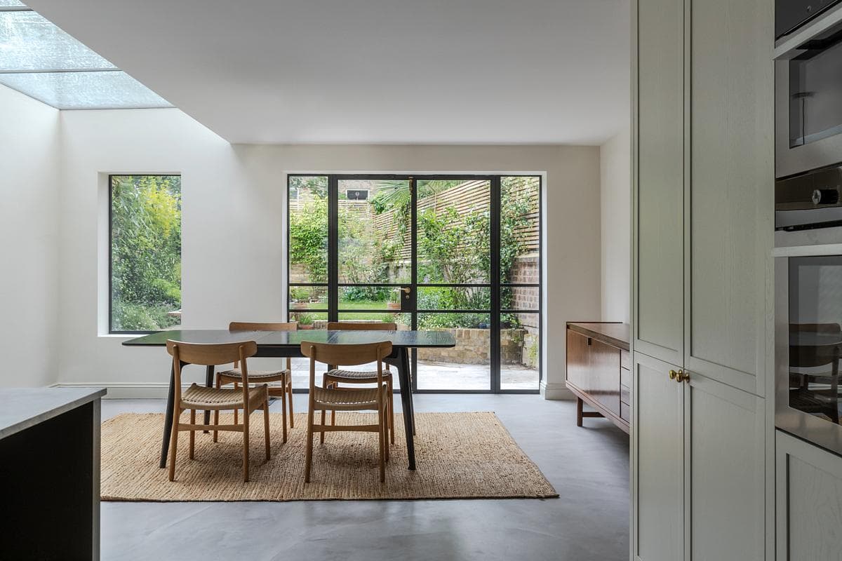 Bright modern dining area featuring natural light, garden views, and minimalist design elements.