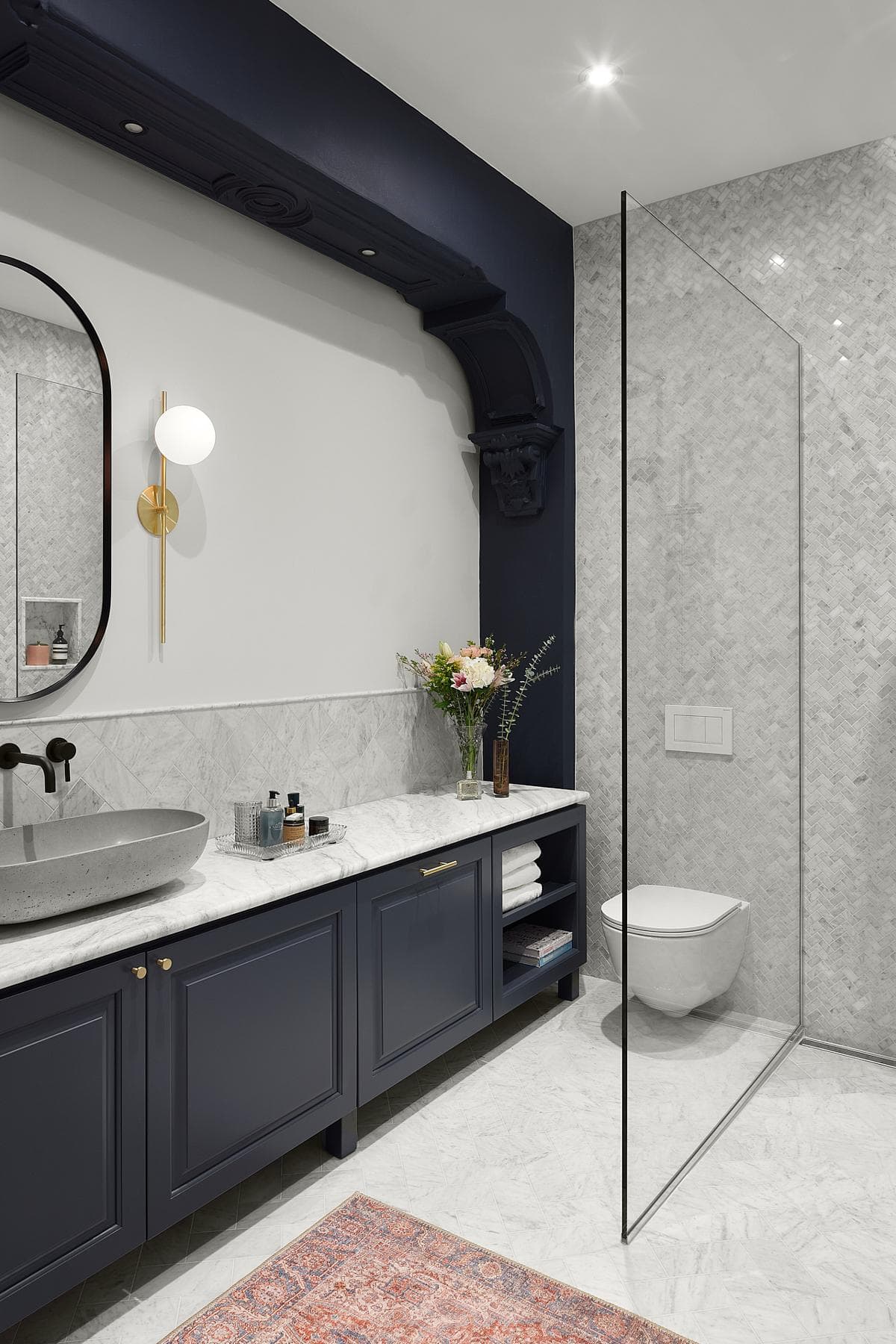 Luxurious modern bathroom featuring marble accents, navy cabinetry, and elegant decor elements.