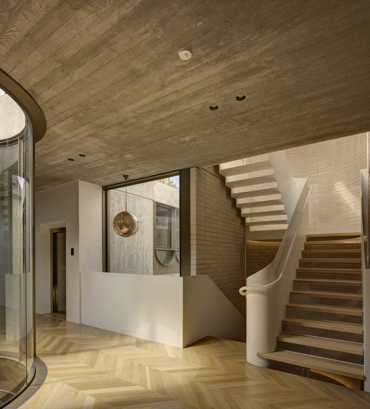 Stylish modern entryway featuring a curved staircase and elegant glass panel design.