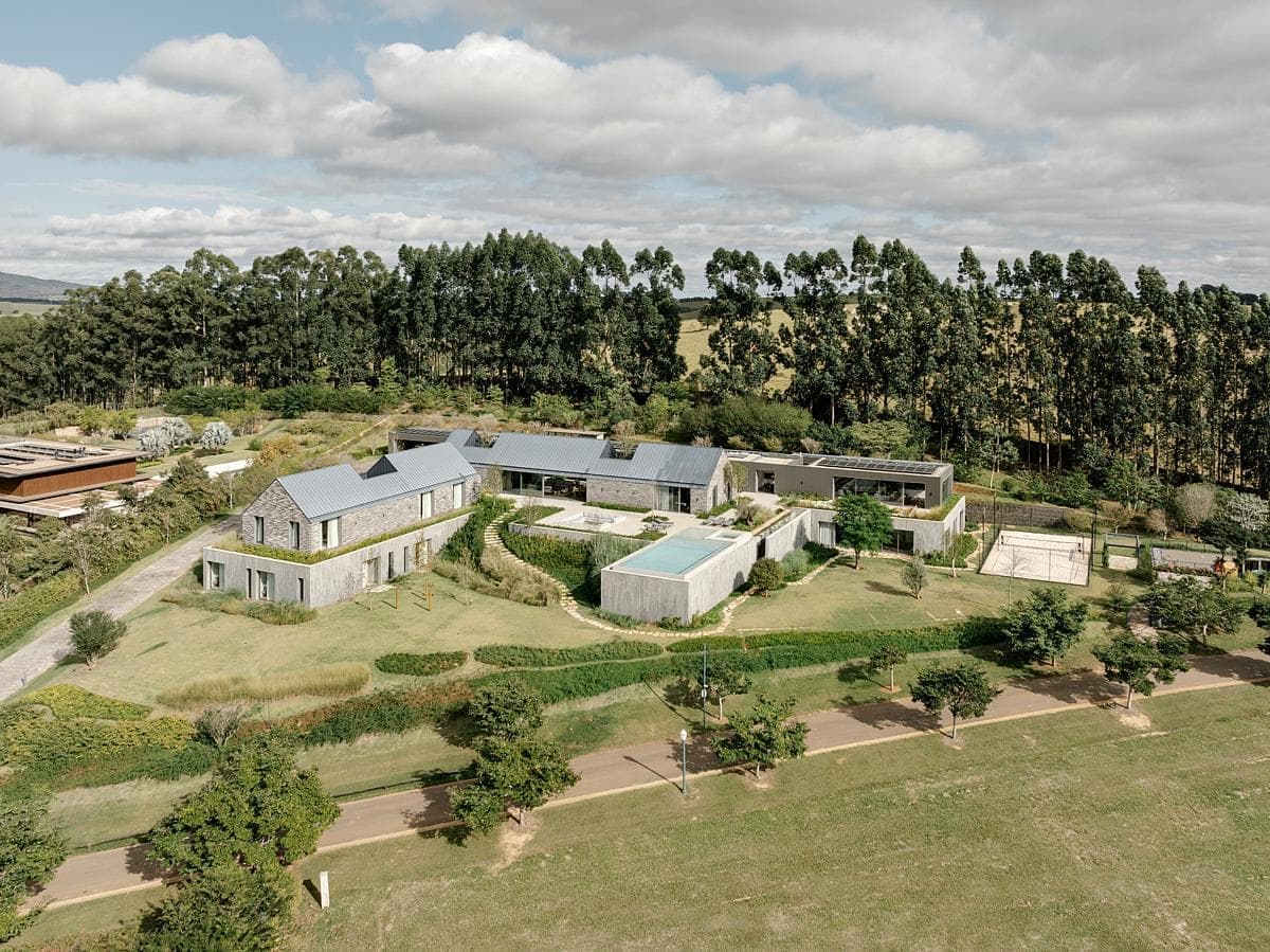 Aerial view of a luxurious modern estate surrounded by lush greenery and serene landscapes.