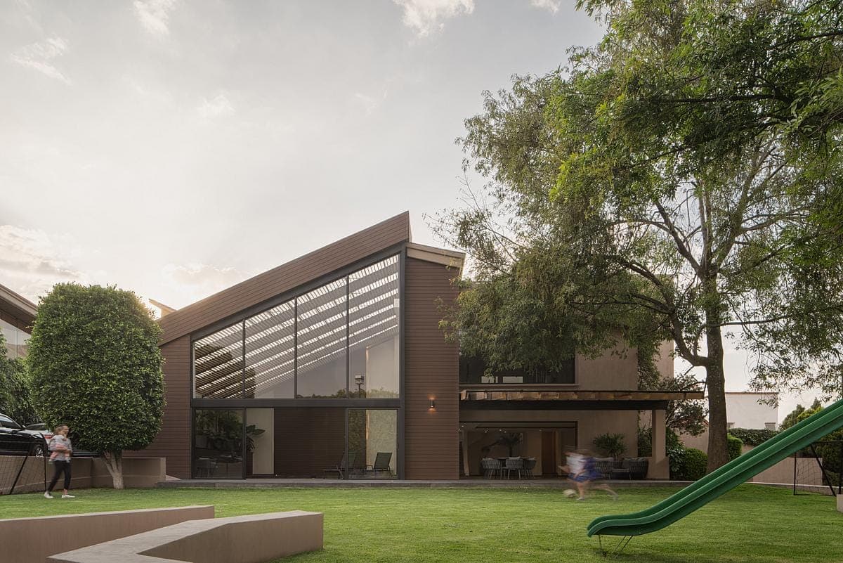 Modern family home with a playground, lush lawn, and sleek architectural design.