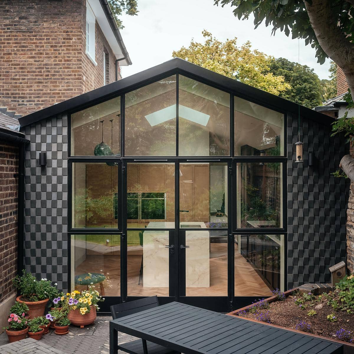 Stunning glass extension seamlessly integrates modern design with lush natural surroundings.