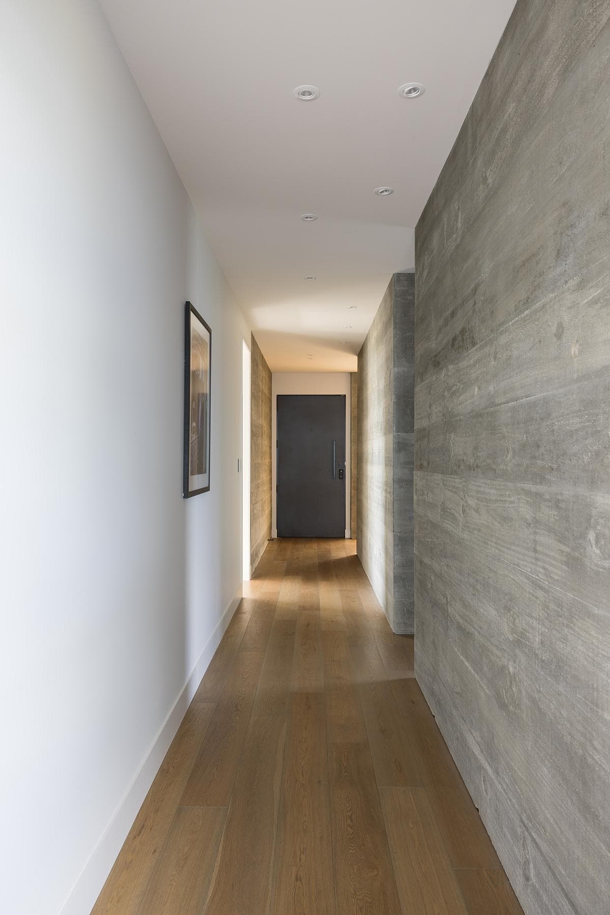 Sleek contemporary hallway design featuring warm accents and inviting dark wooden door.