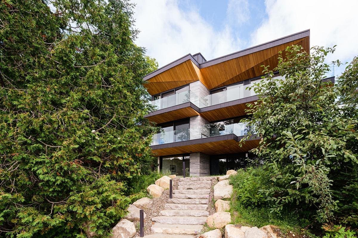 Contemporary house design harmonising with nature through stone, wood, and lush greenery.