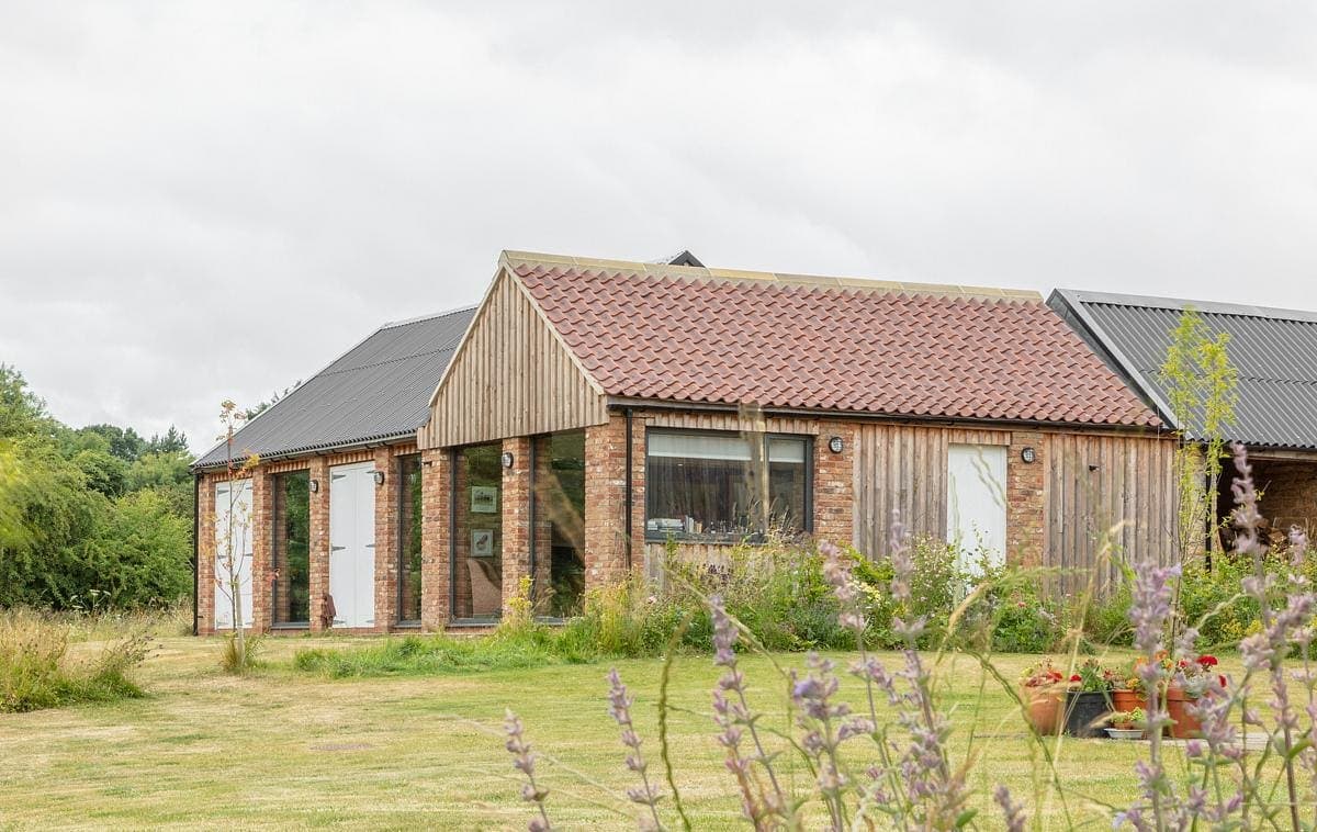 Contemporary home blending with nature, featuring brick and wood, surrounded by serene landscaping.