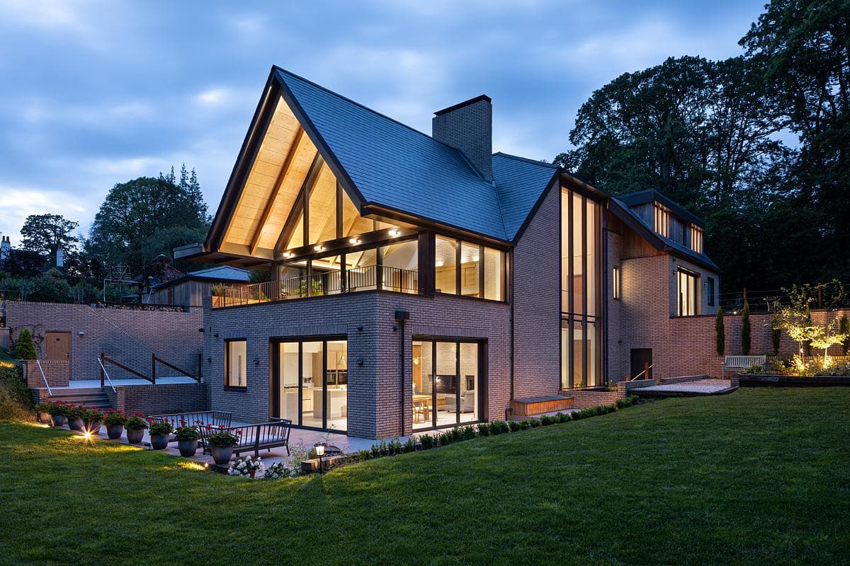 Twilight view of a modern A-frame house blending nature and contemporary design.