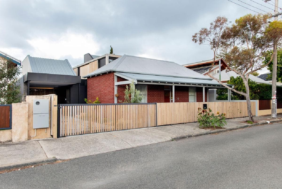 Contemporary home featuring red brick, metal roof, and elegant landscaping in a serene neighbourhood.