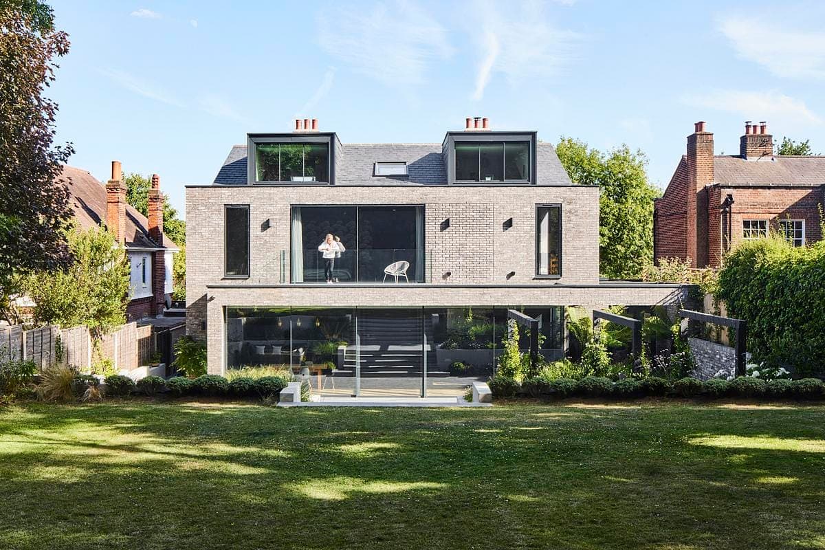 Modern two-storey house with terrace, large windows, and a beautifully landscaped garden.