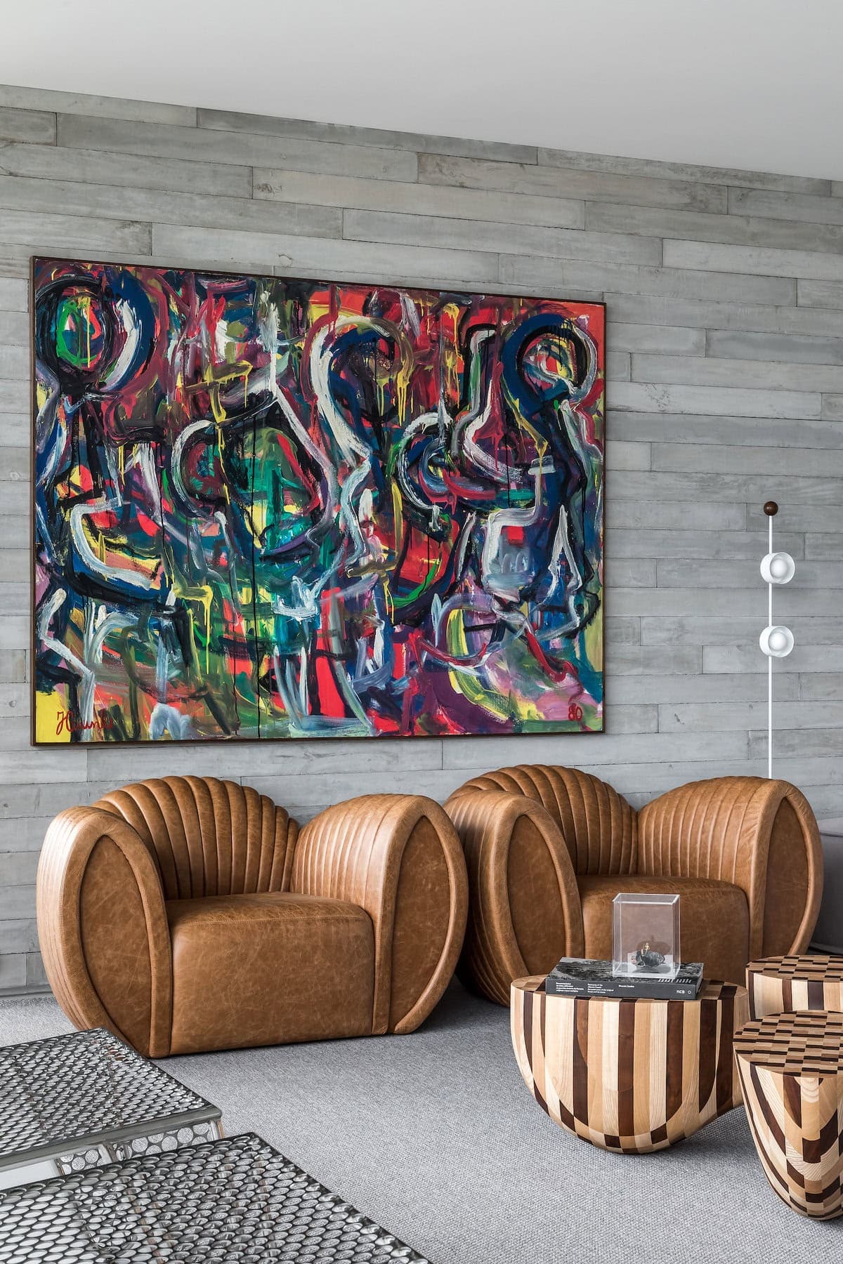 Stylish modern interior featuring vibrant artwork, elegant armchairs, and a unique coffee table.