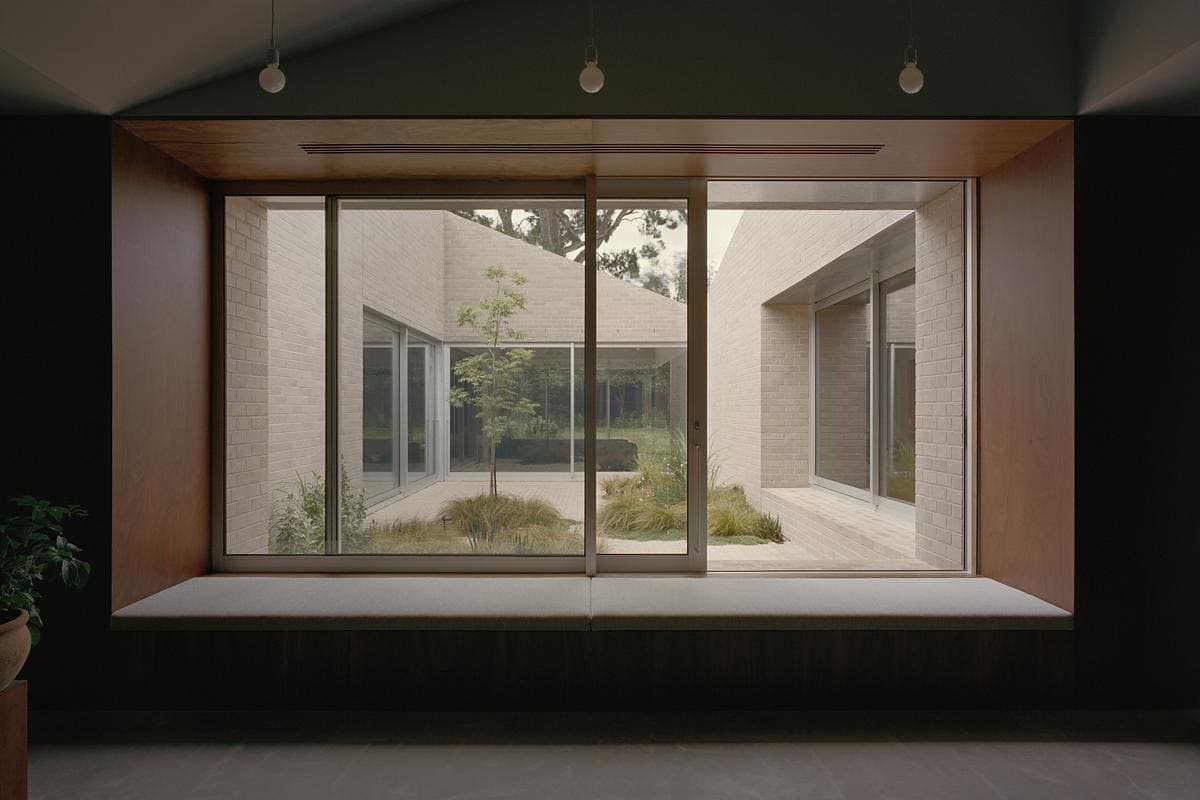 Serene courtyard view from minimalist interior, blending natural light and tranquil design elements.