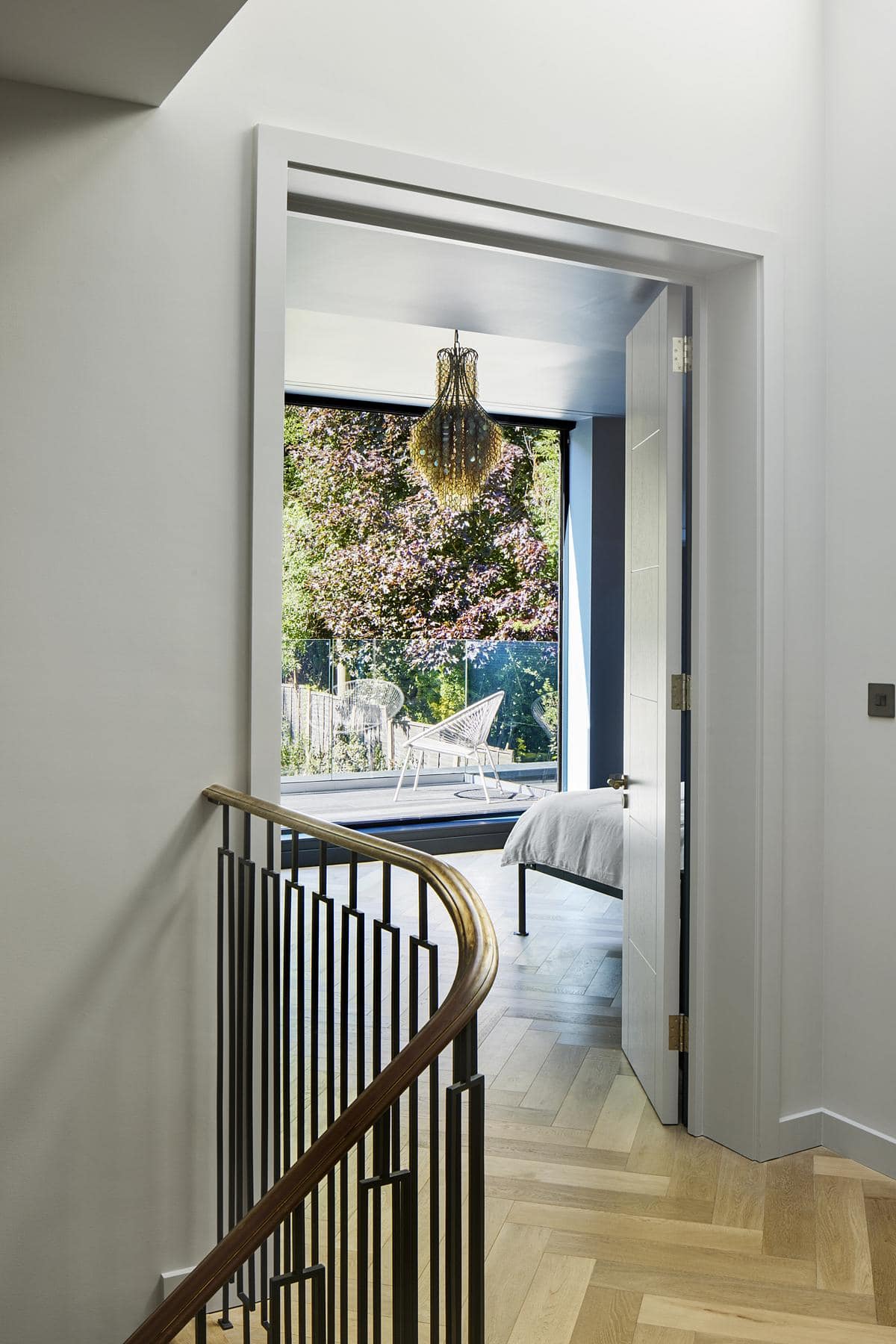 Contemporary hallway leading to a light-filled room with greenery and elegant design elements.