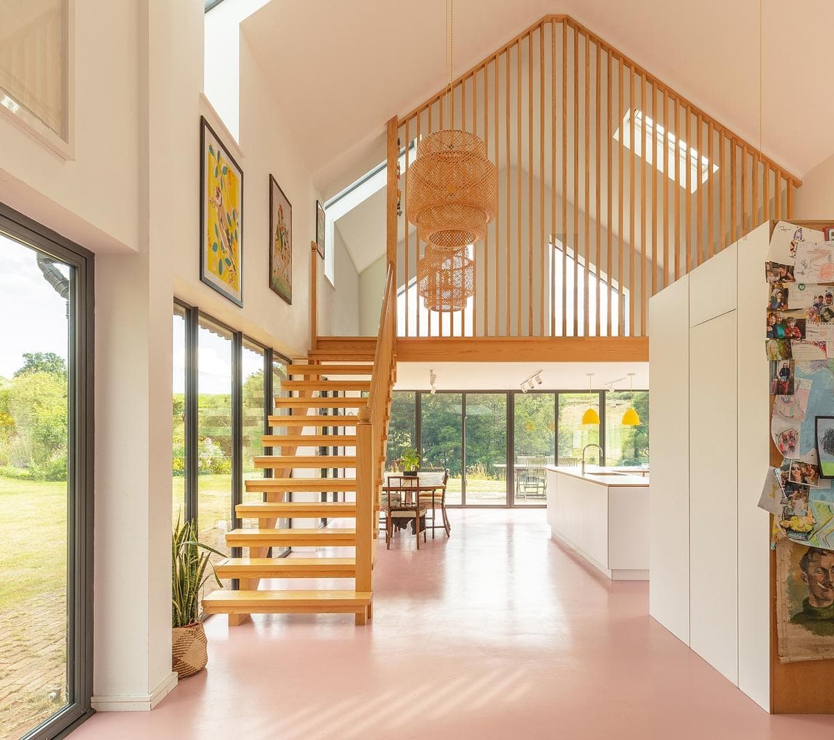 Serene contemporary interior with wooden staircase and large windows, inviting nature indoors.