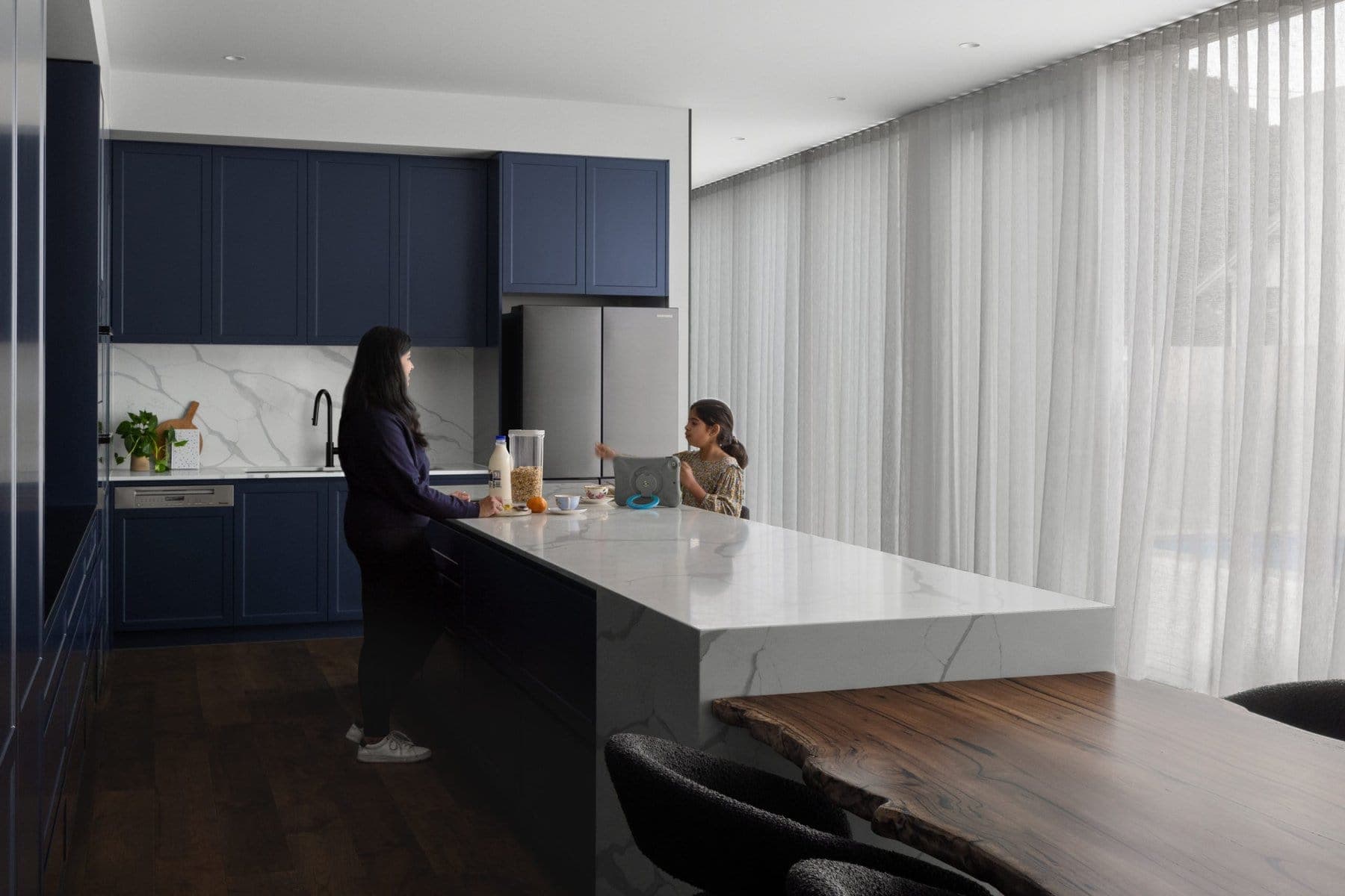 Modern kitchen with navy cabinets, marble countertops, and a large island.