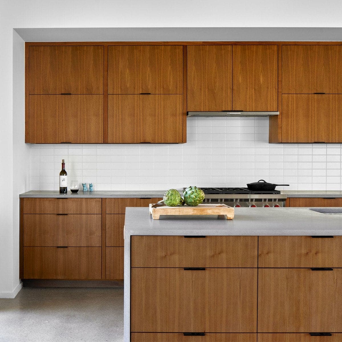Modern kitchen with wooden cabinetry, sleek design, stainless steel range hood, and island.