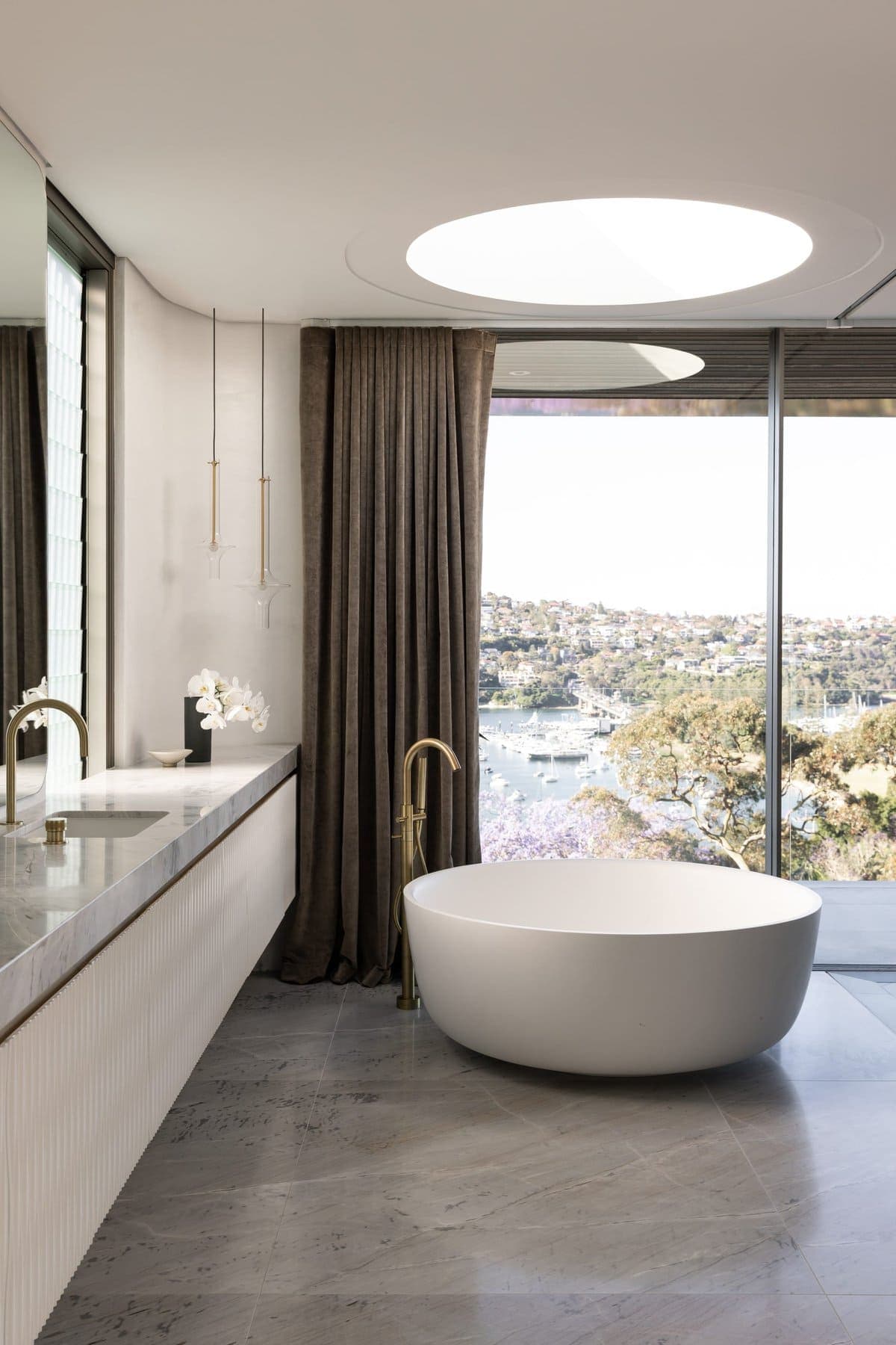Modern luxury bathroom with freestanding bathtub, floor-to-ceiling window, and sleek vanity.