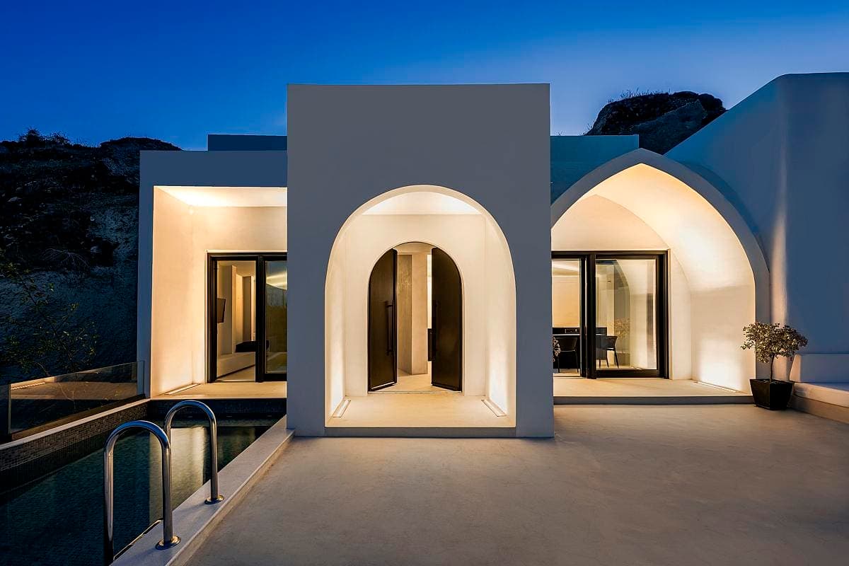 Twilight view of a modern Mediterranean home with elegant archways and a serene pool.