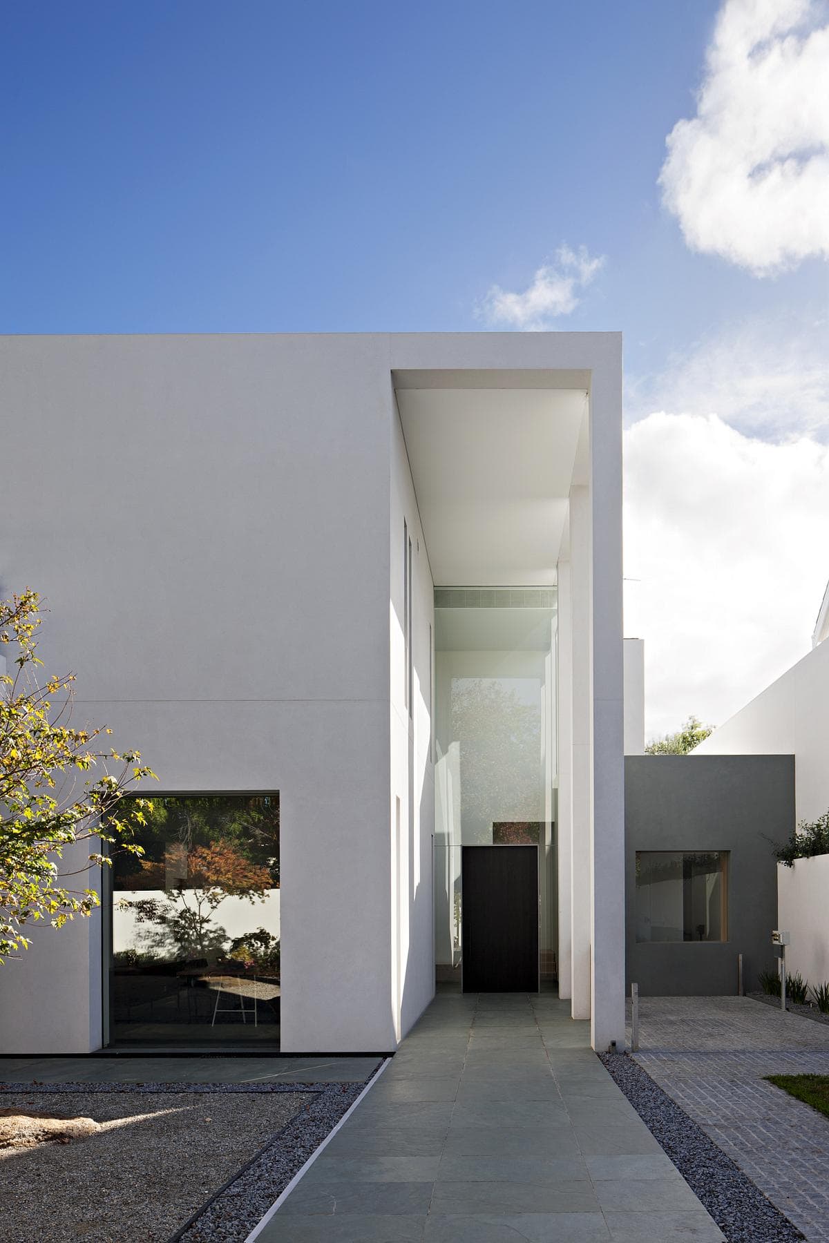 Minimalist white architecture blending with nature, featuring large windows and elegant, inviting design.