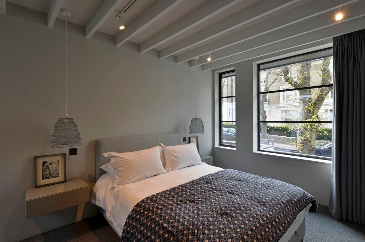 Modern minimalist bedroom with grey tones, floating nightstands, and natural light. Cozy urban retreat.