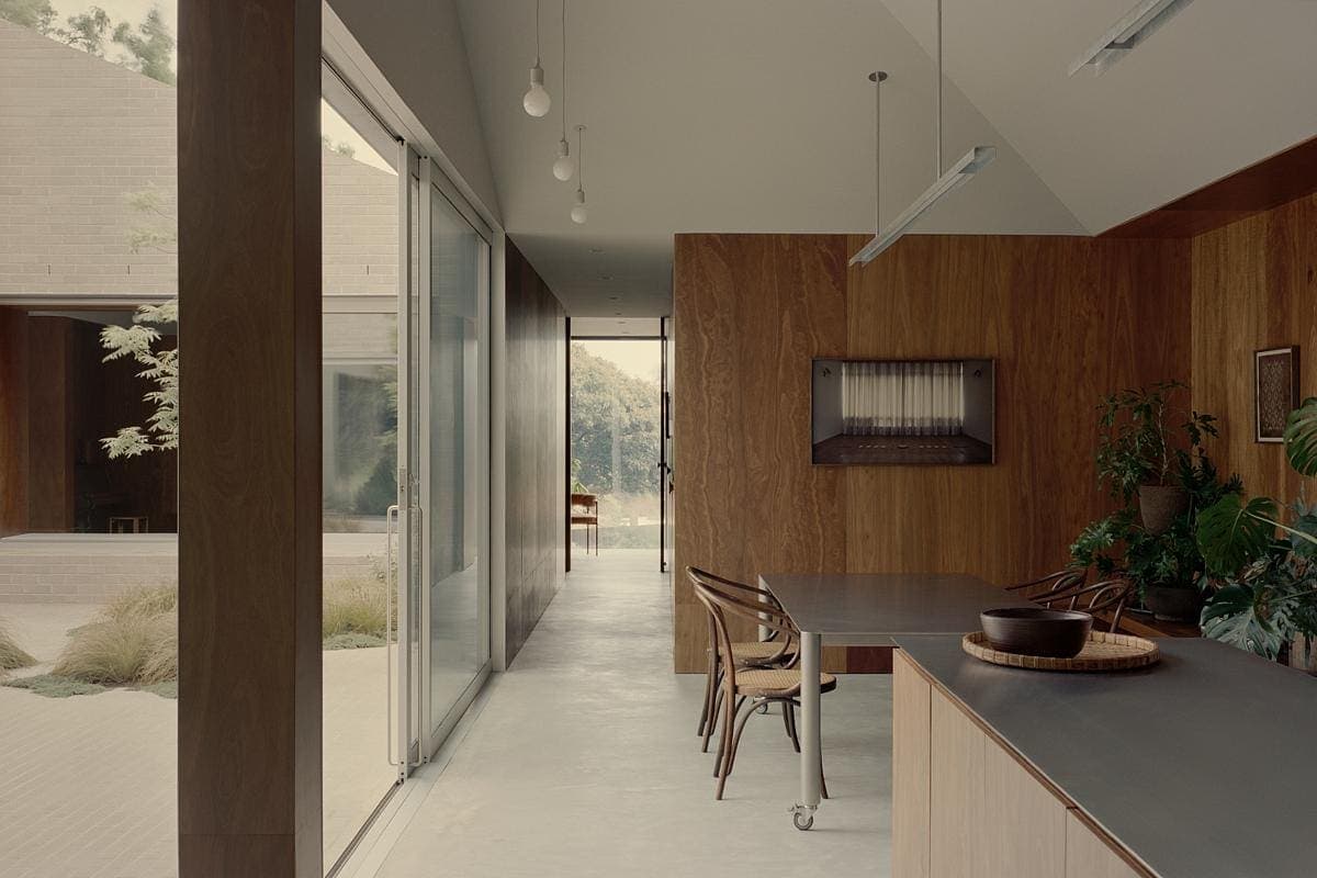 Elegant minimalist dining space seamlessly merging indoor and outdoor elements with natural light.